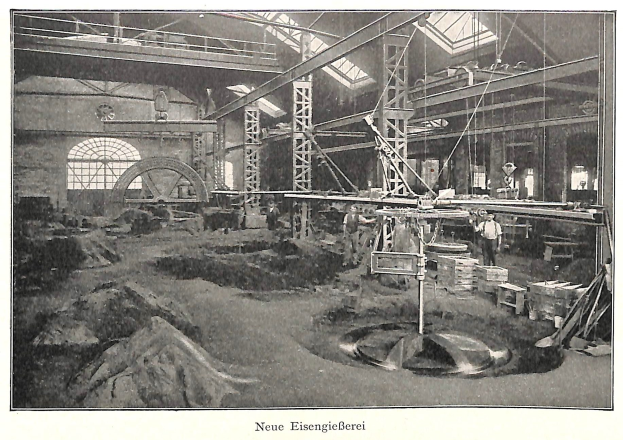 Schwarzes und weißes Foto eines Fabrikinneren mit Arbeitern, die Maschinen bedienen, Metallstangen und -pfosten, beschriftet mit "Neue Eisengießerei, die erste Fabrik in Deutschland" unten.