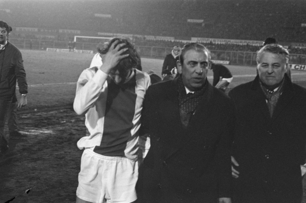 Schwarzes und weißes Bild einer Gruppe von Männern, die auf einem Fußballfeld stehen und nach einem Matchsieg enttäuscht aussehen.