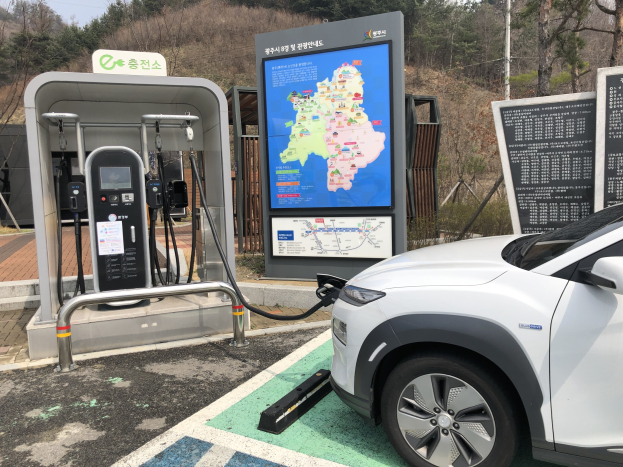 Elektroauto-Laden an einer Station in Seoul, Südkorea, umgeben von Bäumen mit Himmel im Hintergrund.