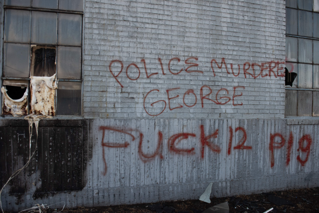 Ein Gebäude mit der Aufschrift "Polizei Mord George Fuck 12 P19" auf der Seite, mit Fenstern und verschiedenen Gegenständen vorne auf dem Boden.