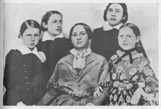 Schwarzes und weißes Foto einer Gruppe von Frauen aus der Frauenwahlrechtsbewegung, mit einer Frau in der Mitte sitzend und anderen Frauen drumherum.