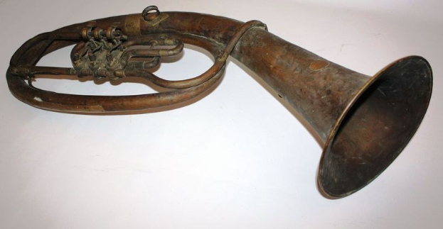 Altes Messinghorn mit glänzender Oberfläche, gebogener Hals und aufgeblähtem Schalltrichter, verziert mit kunstvollen Gravuren, auf einem weißen Hintergrund.