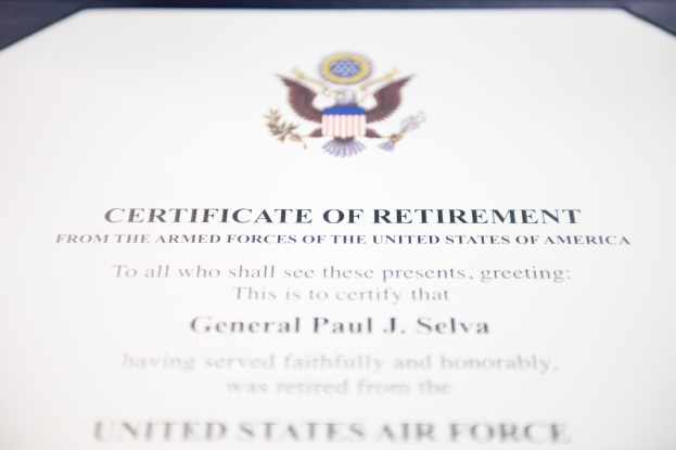 Blau gerahmtes Entlassungszertifikat der United States Air Force mit einem zentralen Sternschild-Logo innerhalb eines Lorbeerkranzes und einer "Retirement"-Bannertafel, alles in schwarzer Schrift.