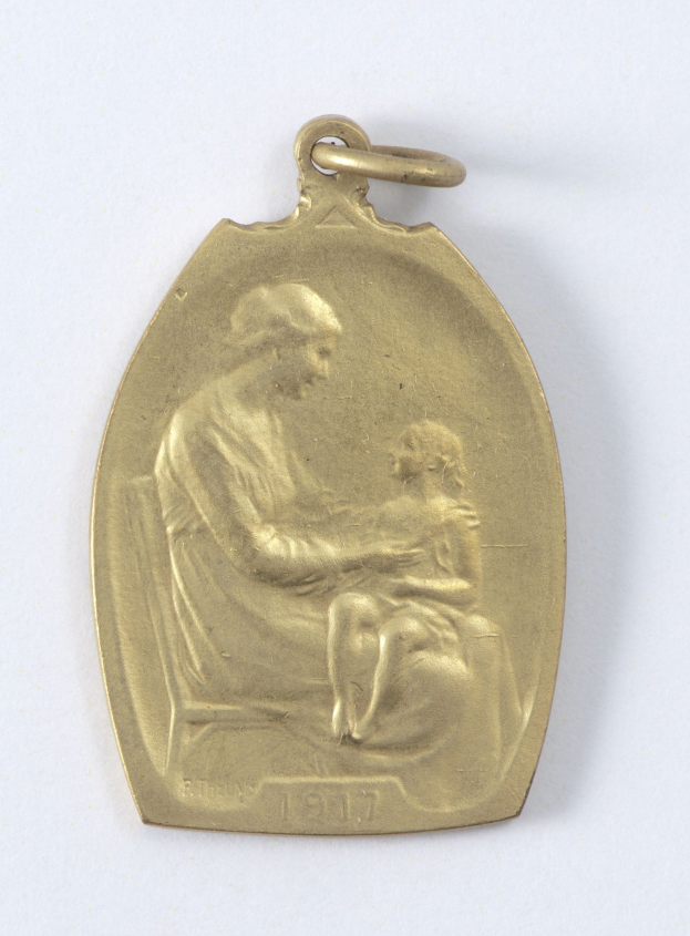 Goldmedaille mit einer Gravur einer Frau in einem weißen Kleid mit einem Dutt, die ein Kind hält, beide schauen einander mit Ausdrucken von Zärtlichkeit und Verwunderung an, beschriftet mit "Mutter und Kind."