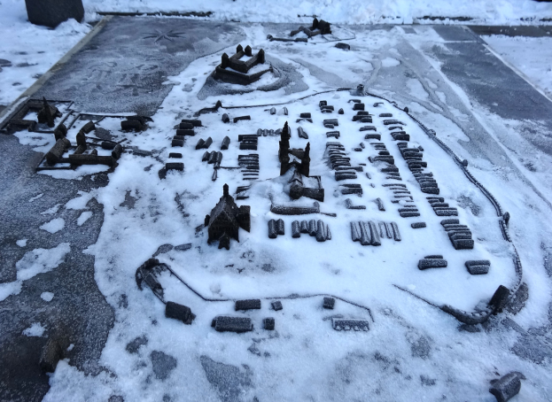 Eine Stadtkarte ist auf einem schneebedeckten Boden zu sehen, umgeben von Gebäuden und Gegenständen, mit einem schneebedeckten Hintergrund, der eine friedliche Winterszene schafft.