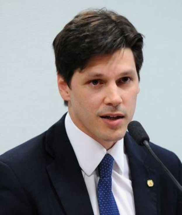 Ein Mann im Anzug und mit Krawatte spricht vor einer Wand in ein Mikrofon und scheint eine Erklärung abzugeben.