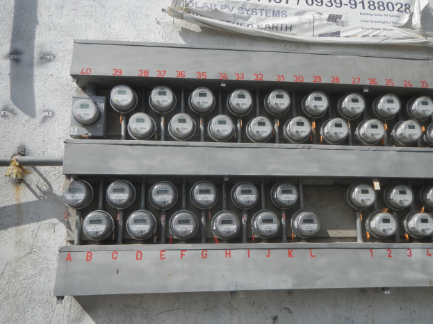 Nahaufnahme eines Elektrizitätszählers an der Seite eines Gebäudes mit einem Banner oben mit Text.