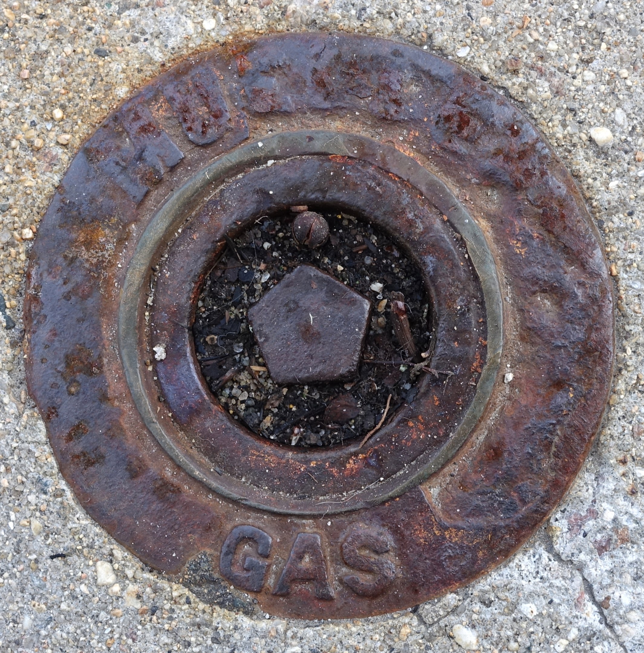 Rostiger Metall-Schachtobel auf dem Boden mit dem Wort "Gas" darauf.