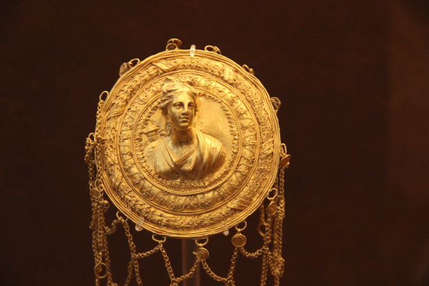 Goldene Medaille mit einer Frauengestalt auf dunklem Hintergrund mit feiner und luxuriöser Verzierung.